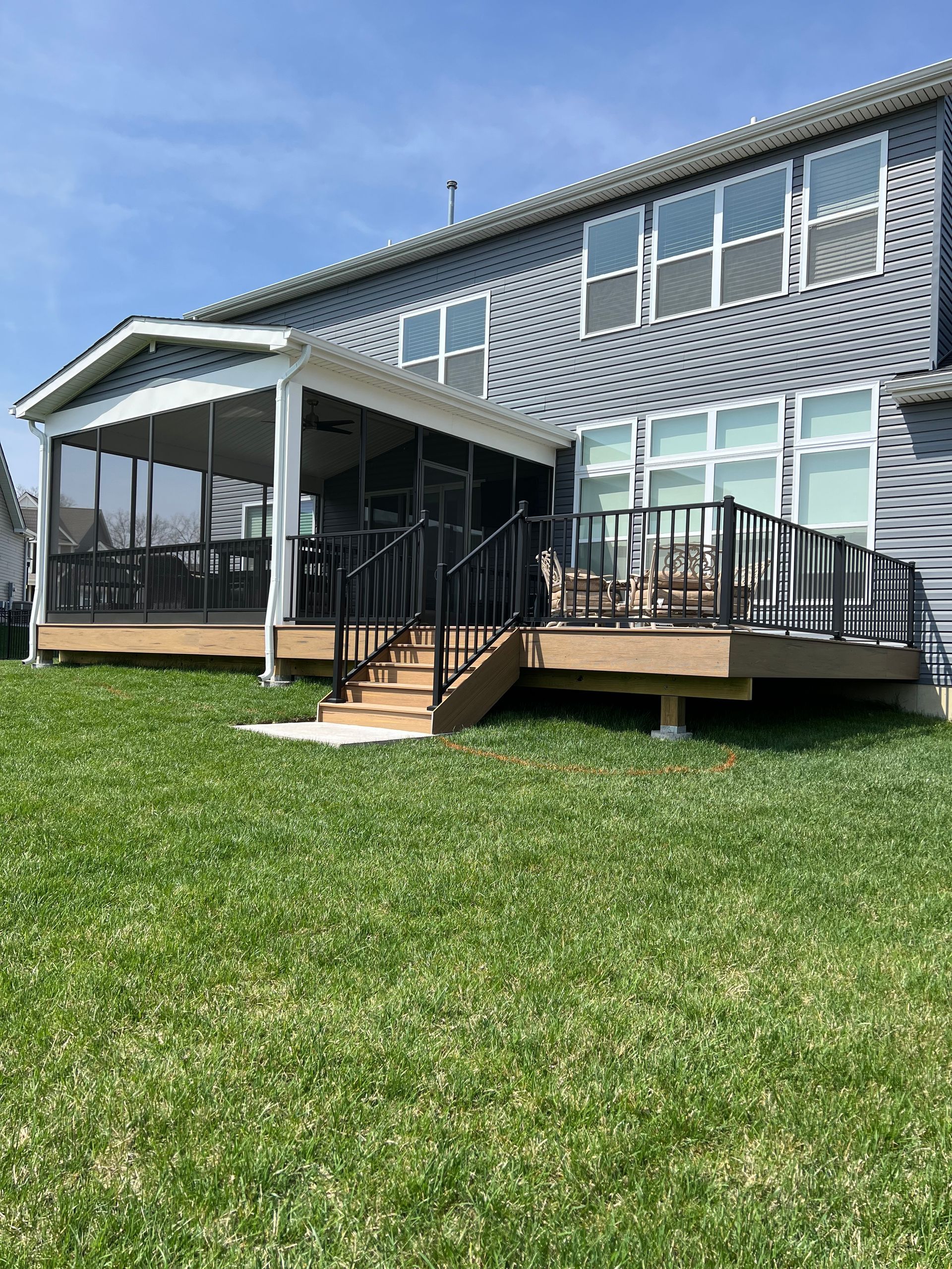 A large house with a large deck and screened in porch.