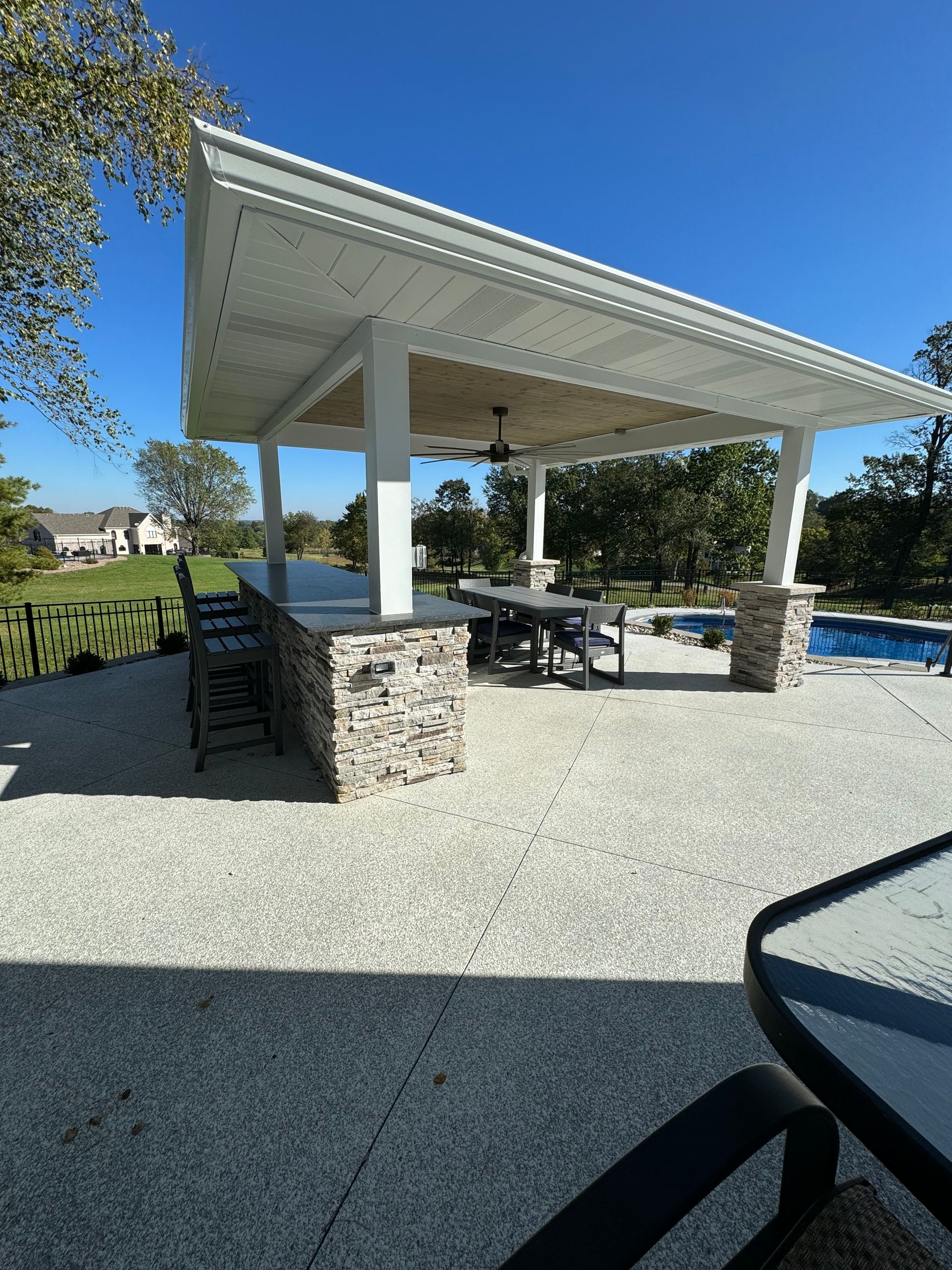 A gazebo with a table and chairs is sitting next to a pool.