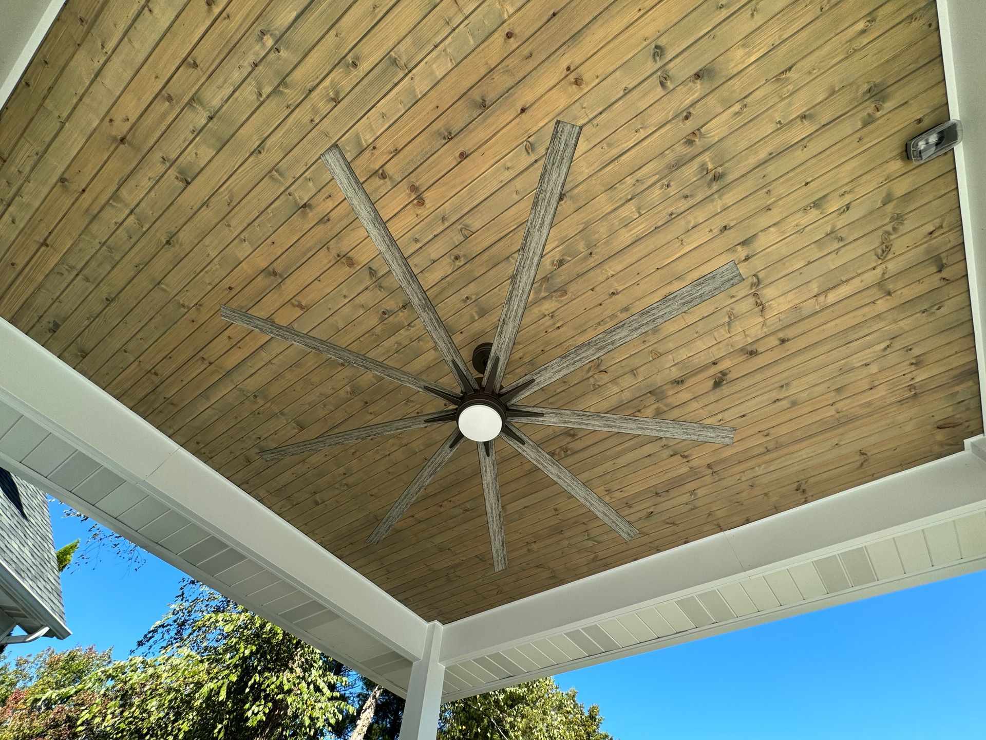 A ceiling fan is hanging from the ceiling of a porch.