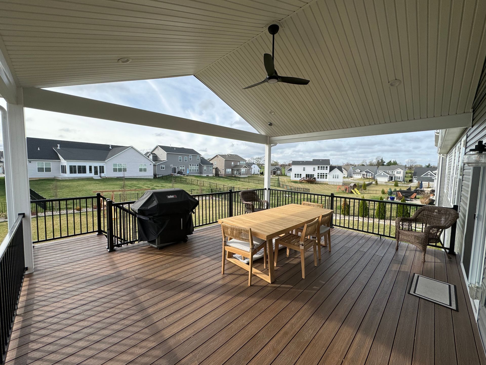 A large deck with a table and chairs and a ceiling fan.