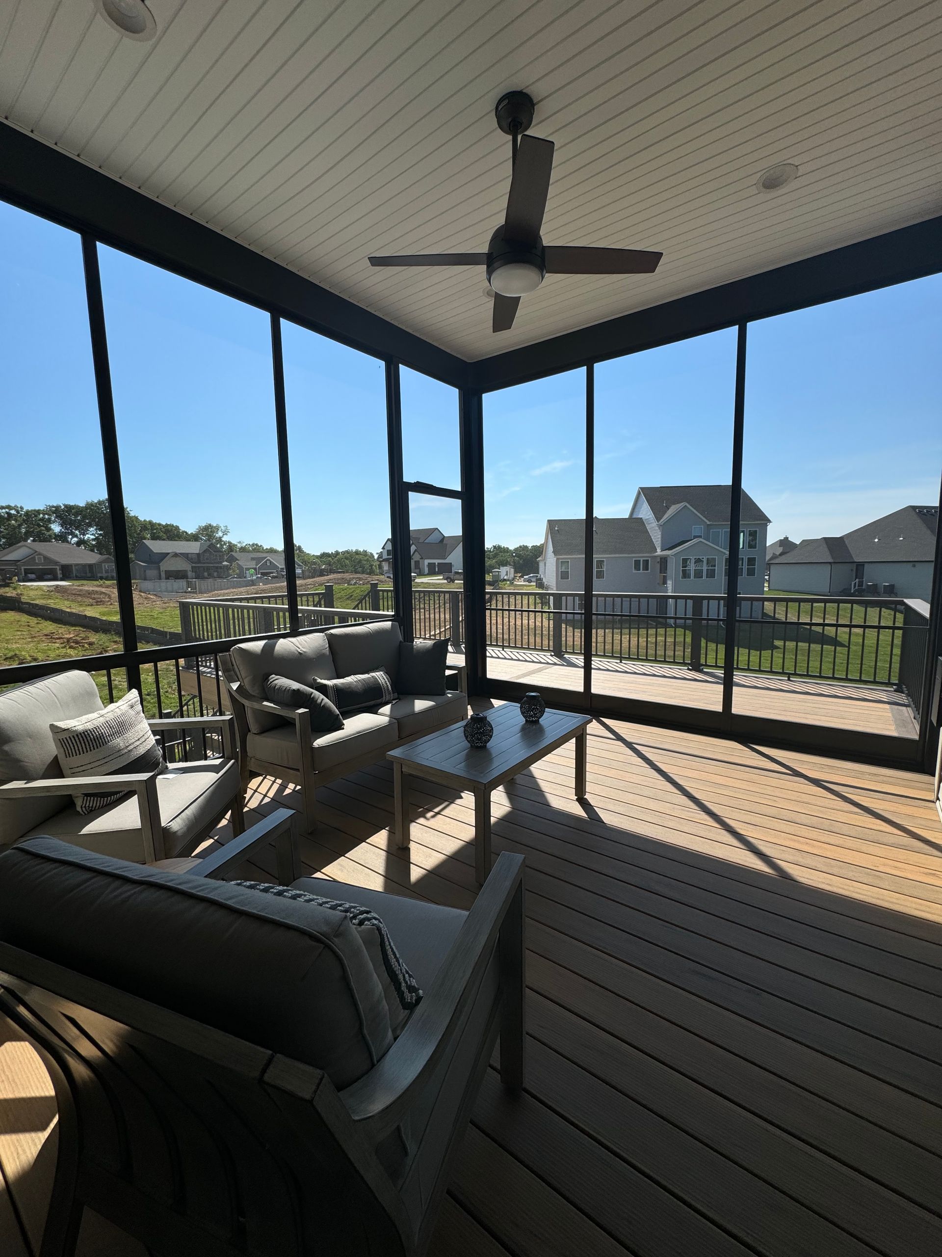 A screened in porch with furniture and a ceiling fan