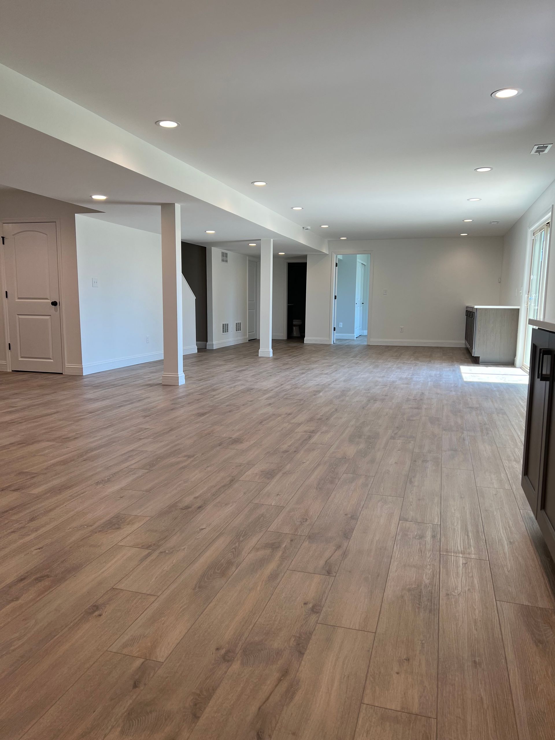 A large empty room with hardwood floors and white walls.