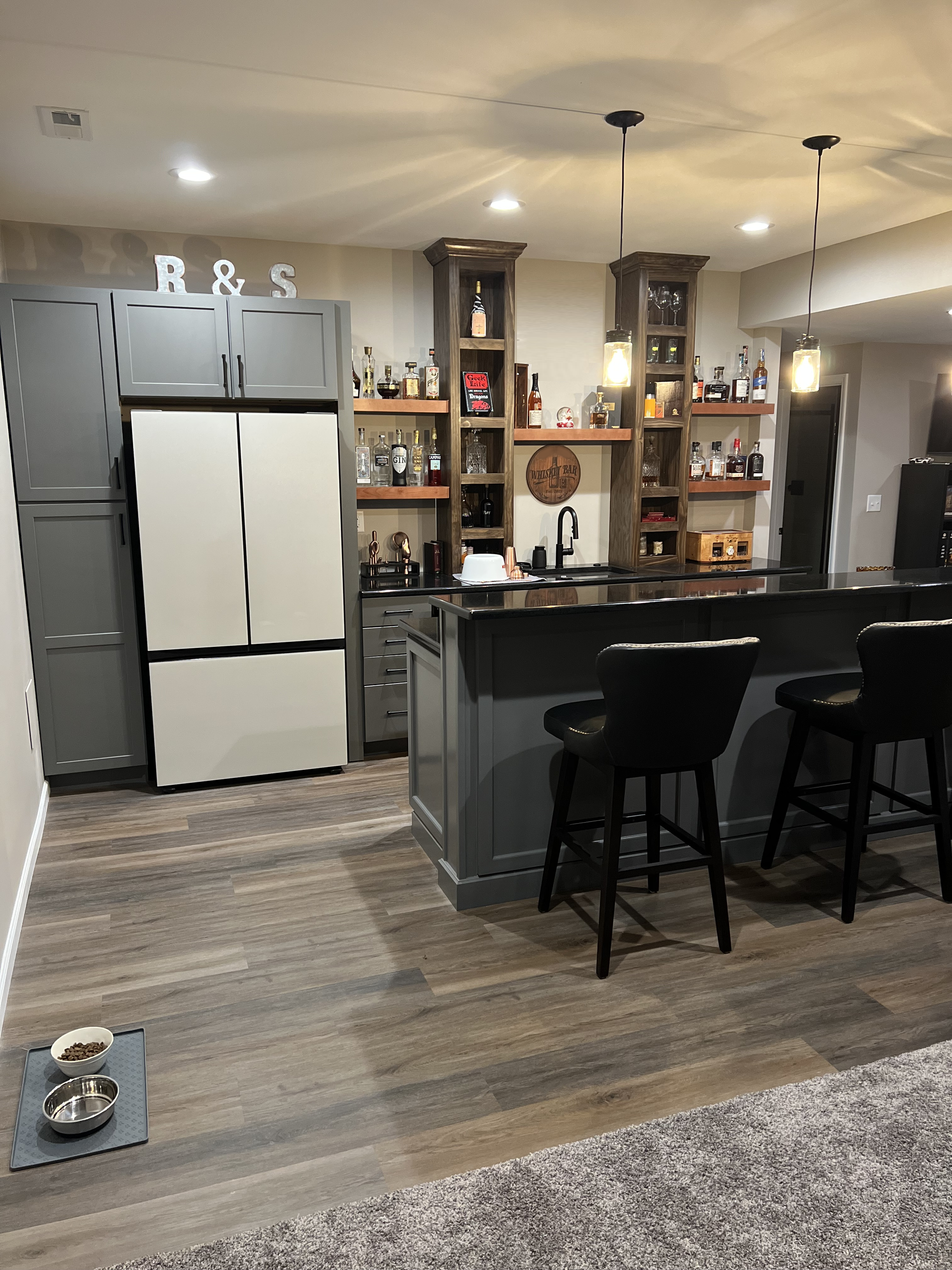 A kitchen with a bar and stools and a refrigerator