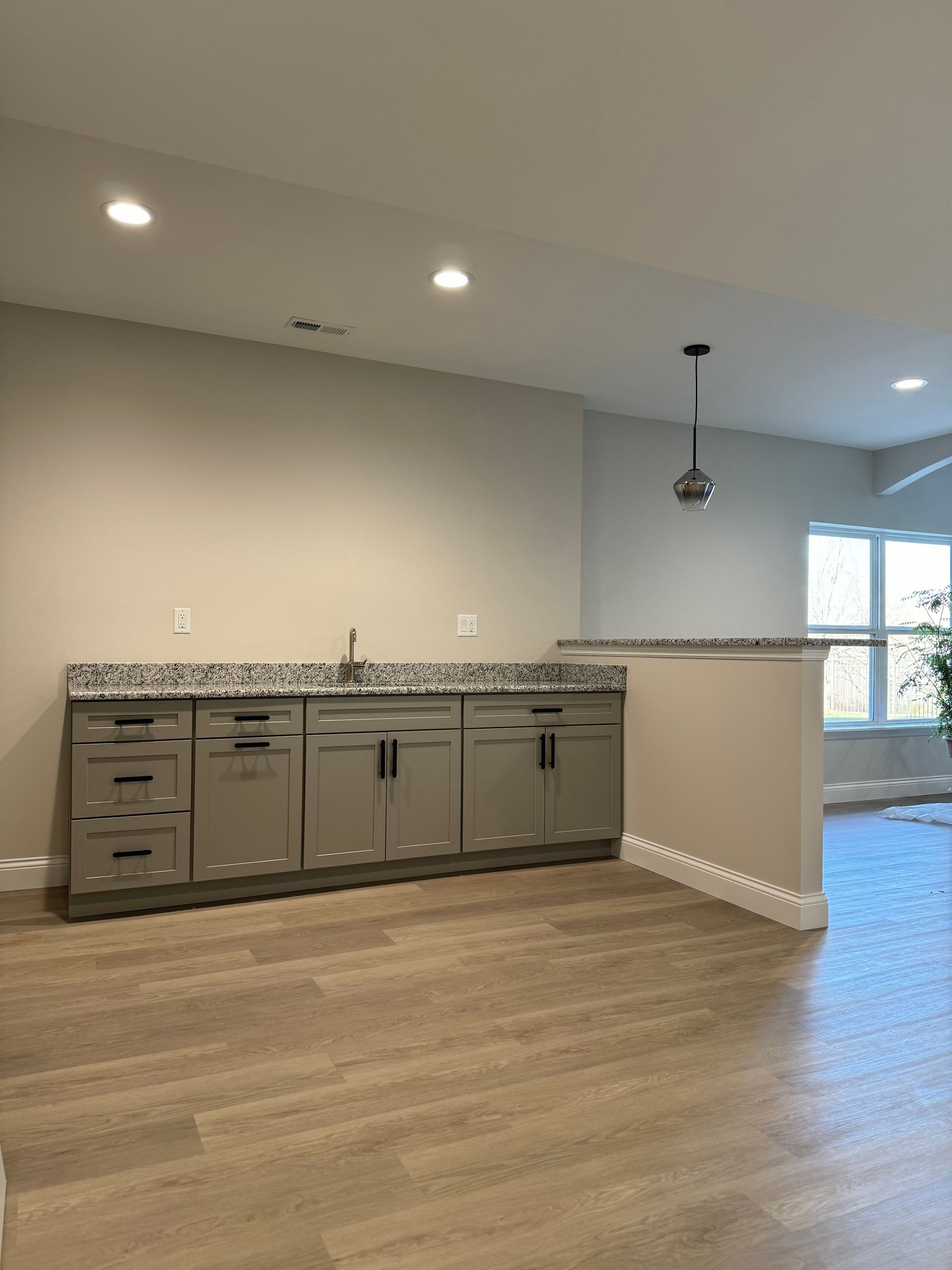 An empty kitchen with gray cabinets and granite counter tops