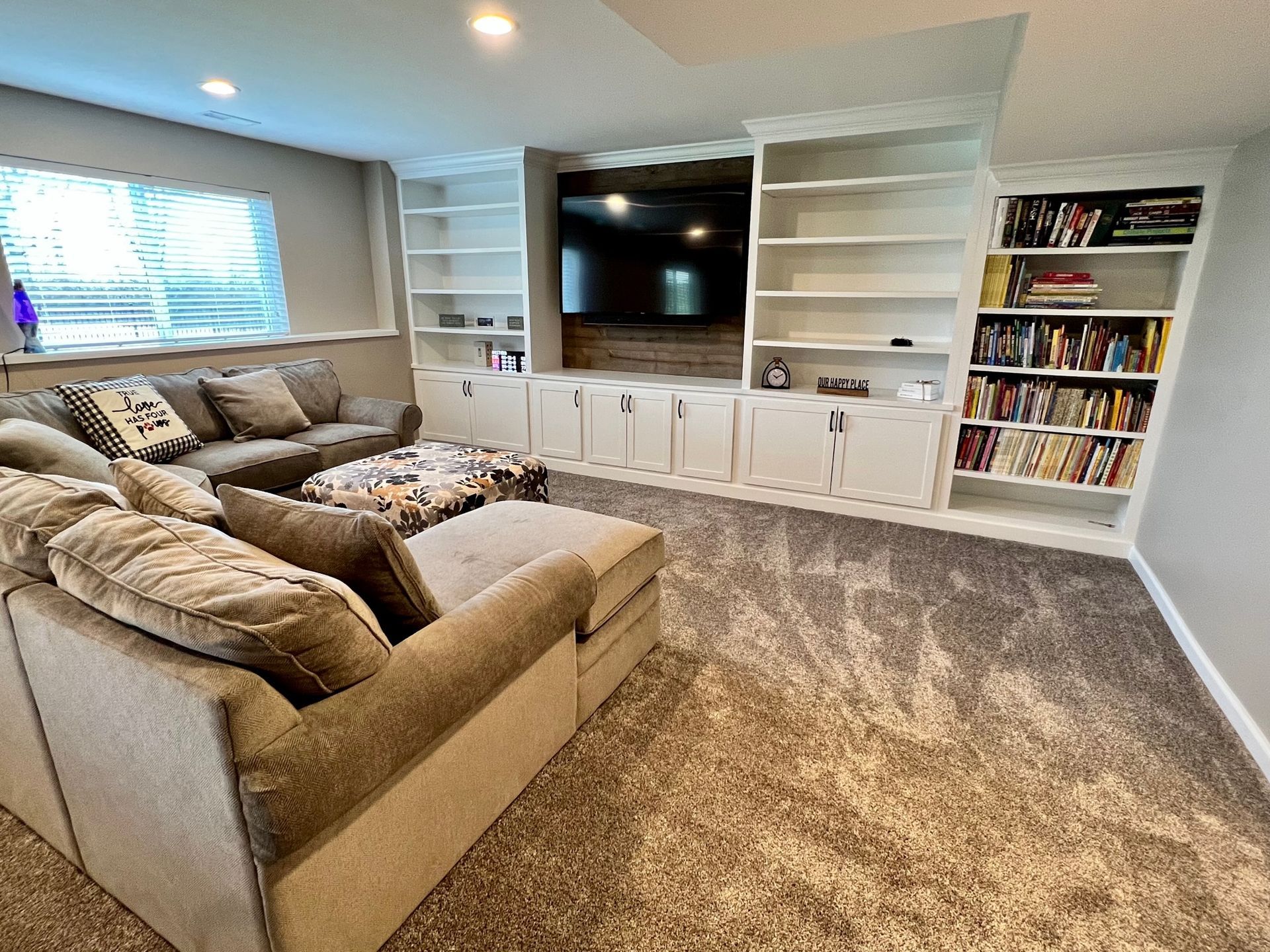 A living room with a couch, chair, bookshelf and television.