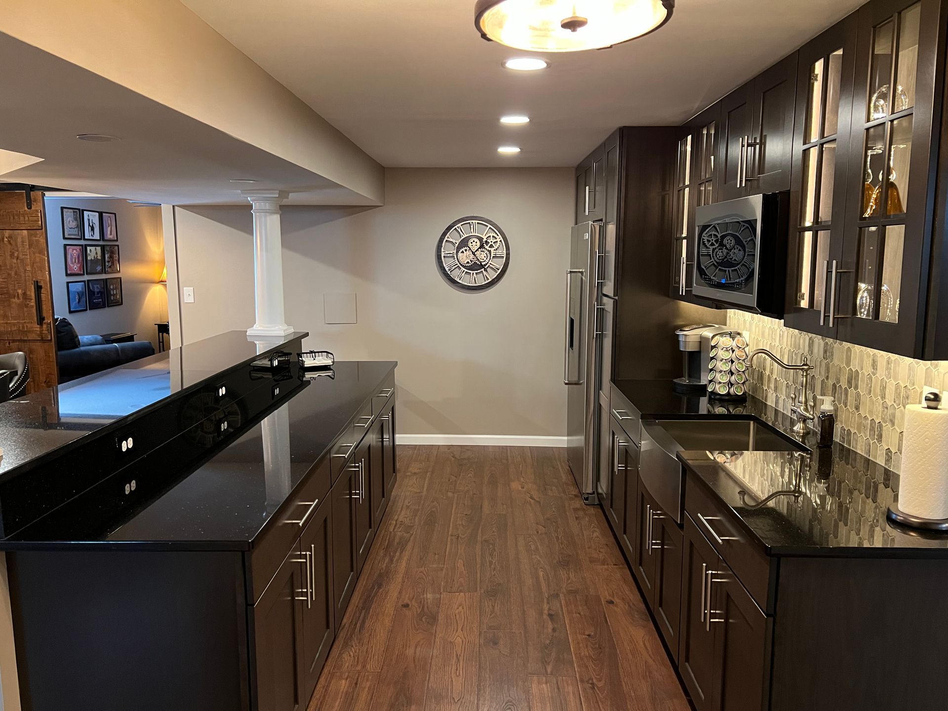 A kitchen with black cabinets and a clock on the wall