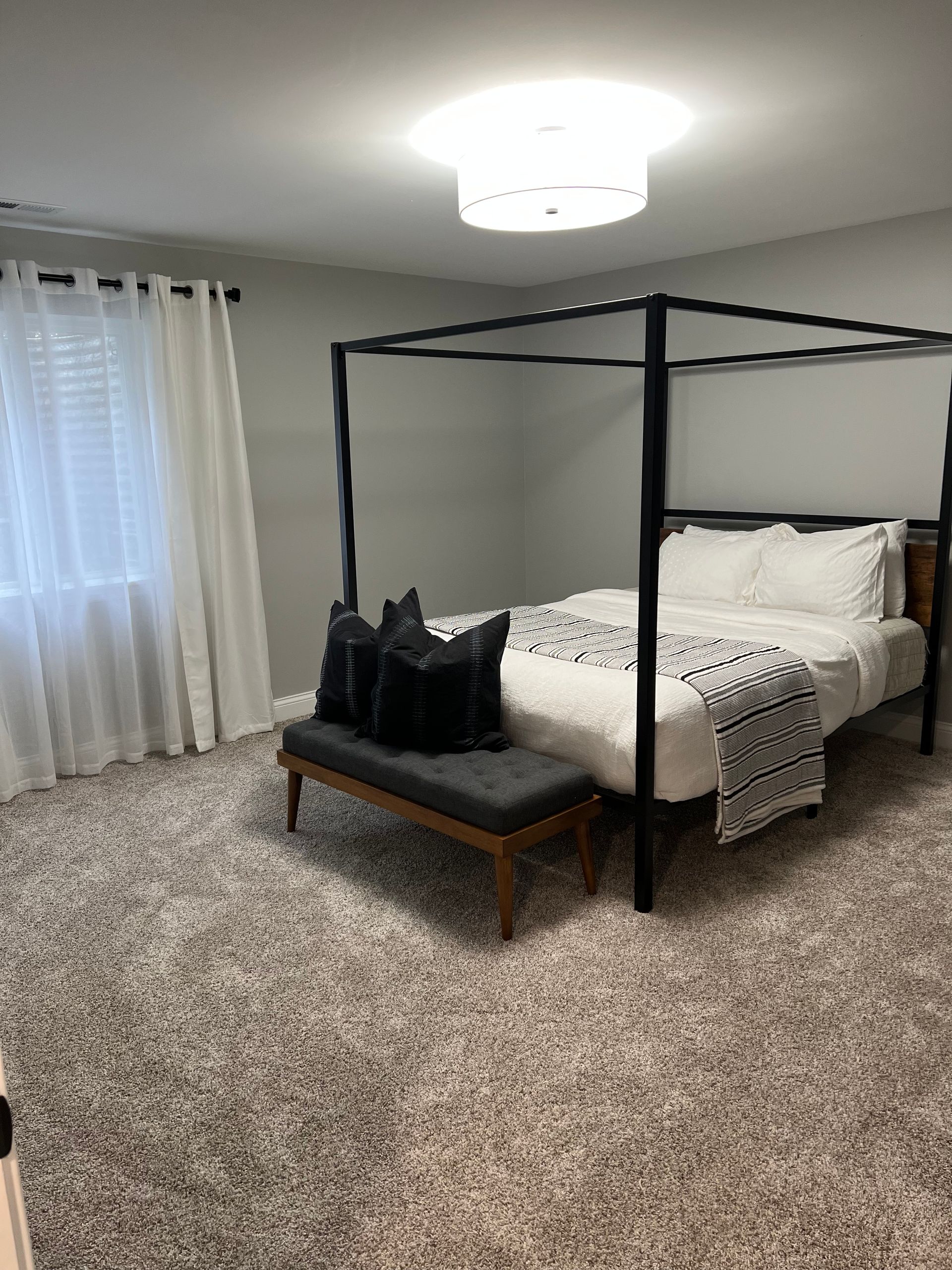 A bedroom with a canopy bed and a bench.