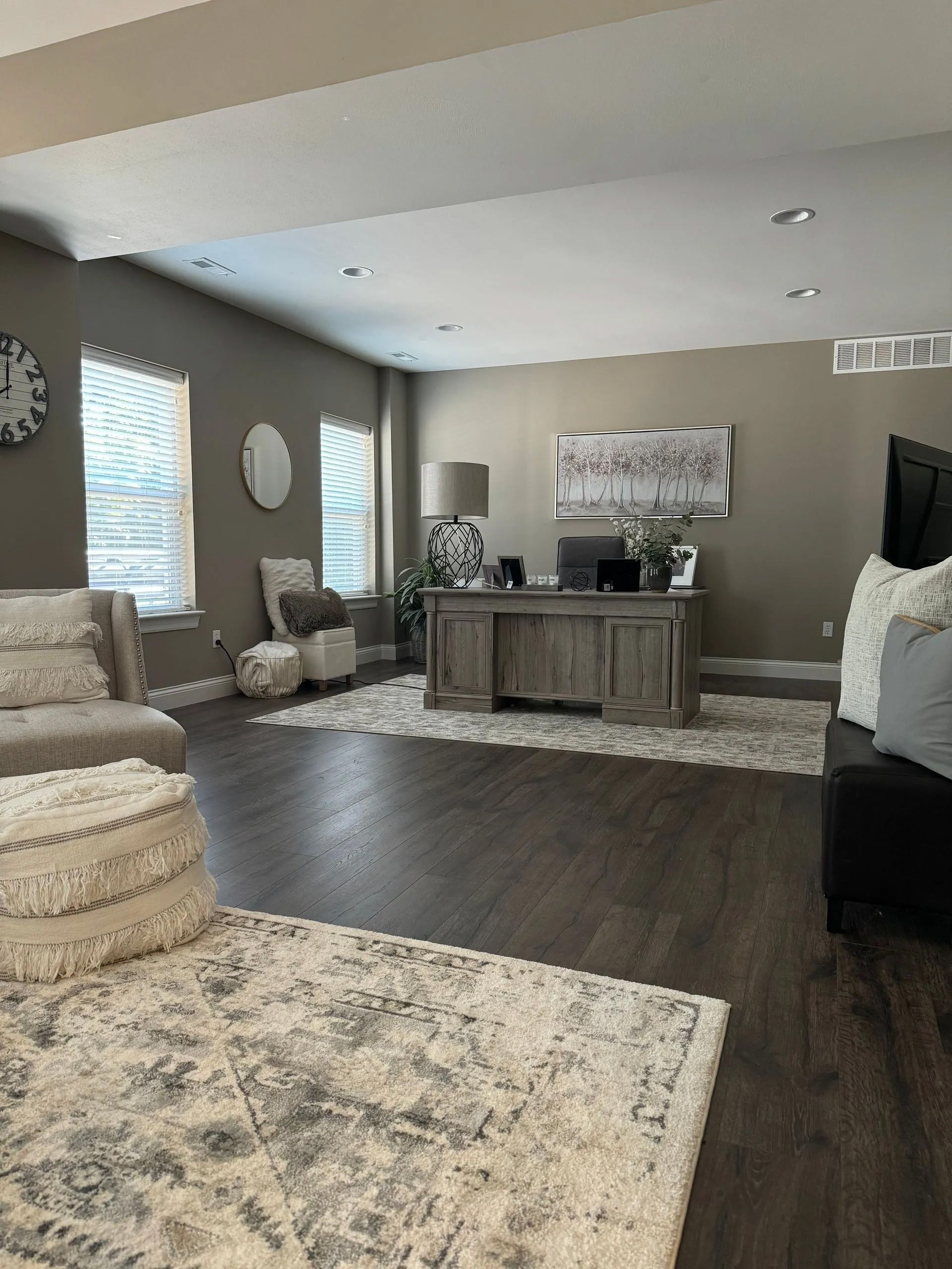 A living room with a desk, chairs, and a rug