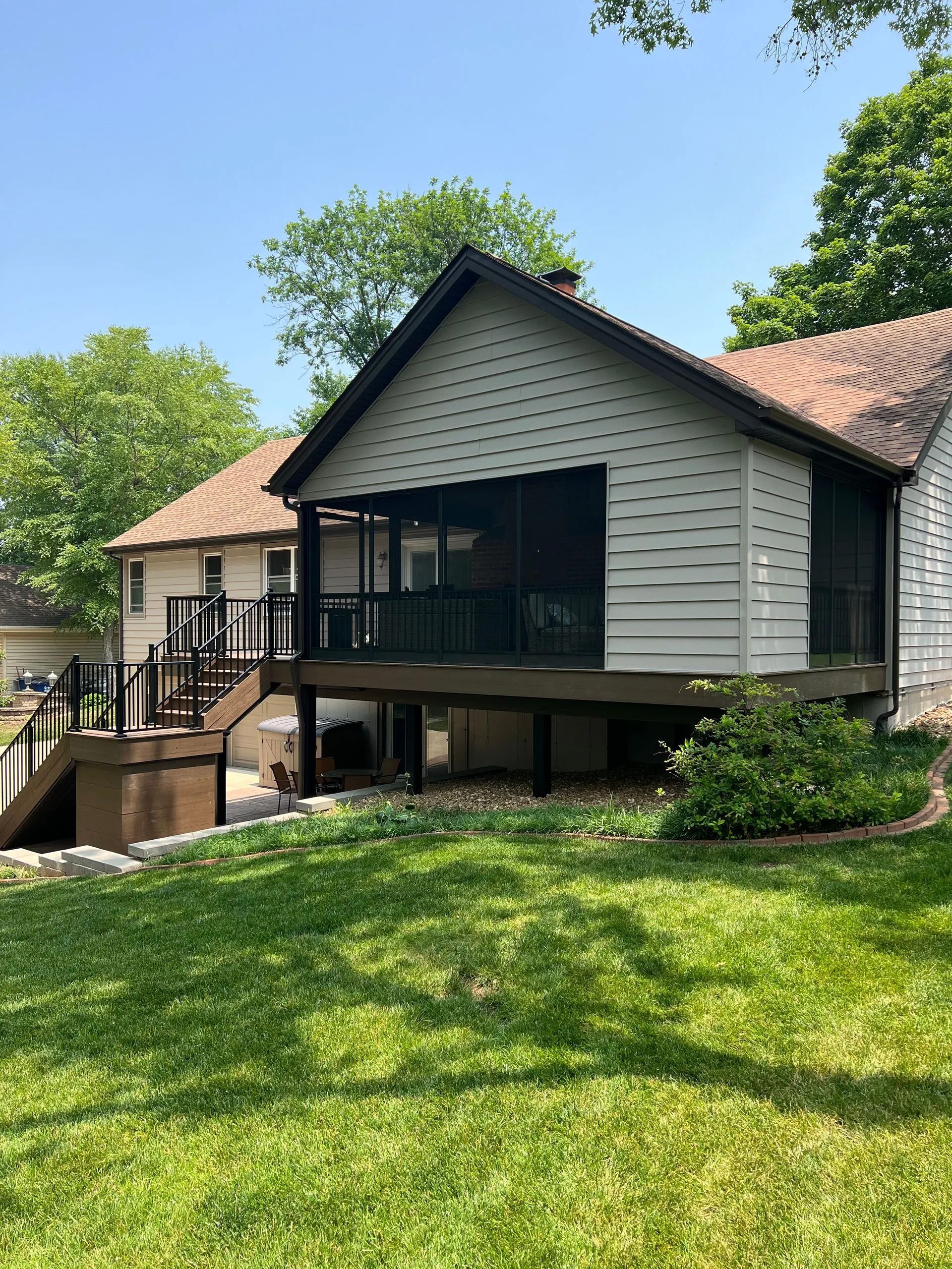 A house with a screened in porch and a large lawn in front of it.