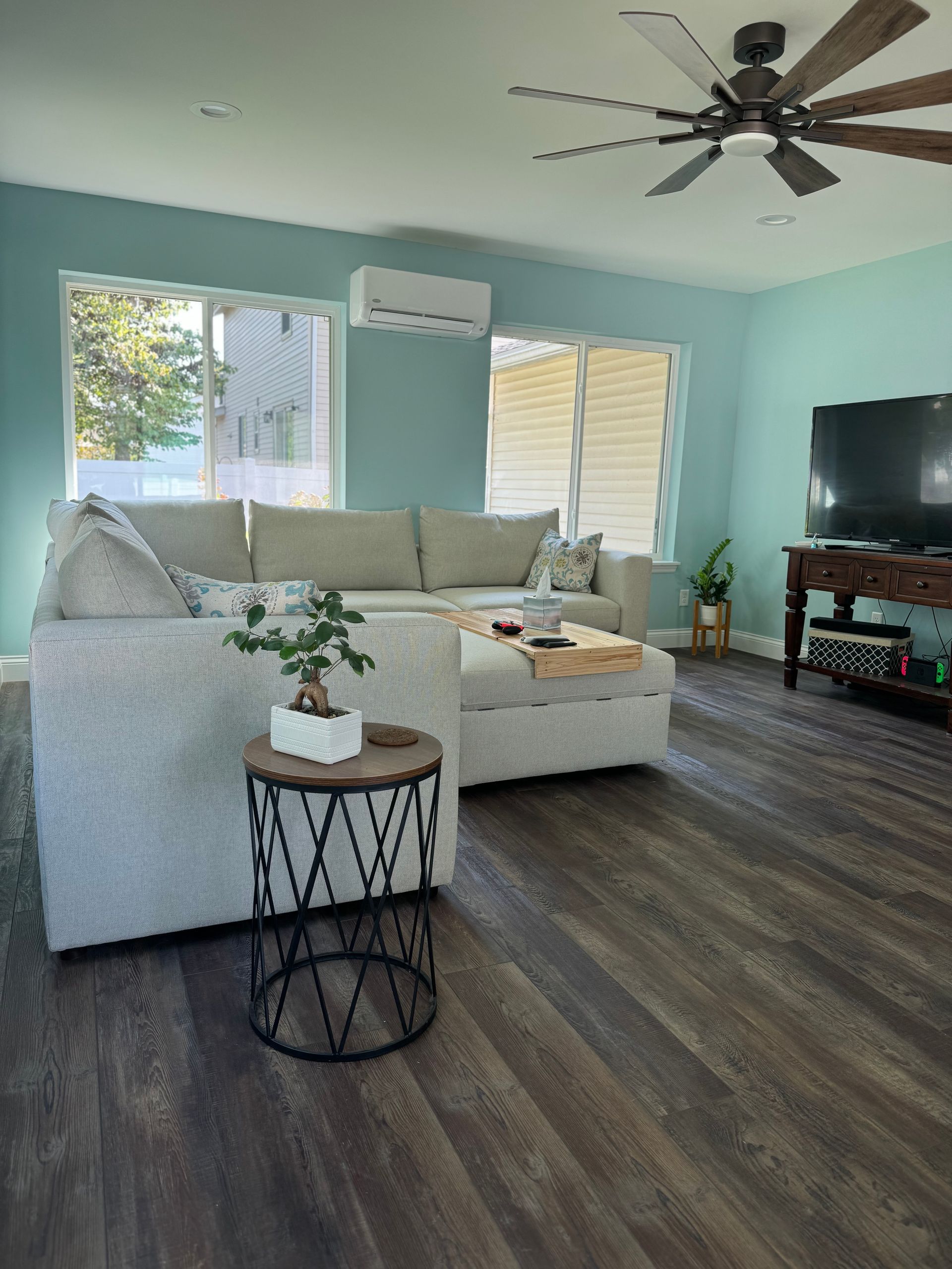 A living room with a couch, table, television and ceiling fan.