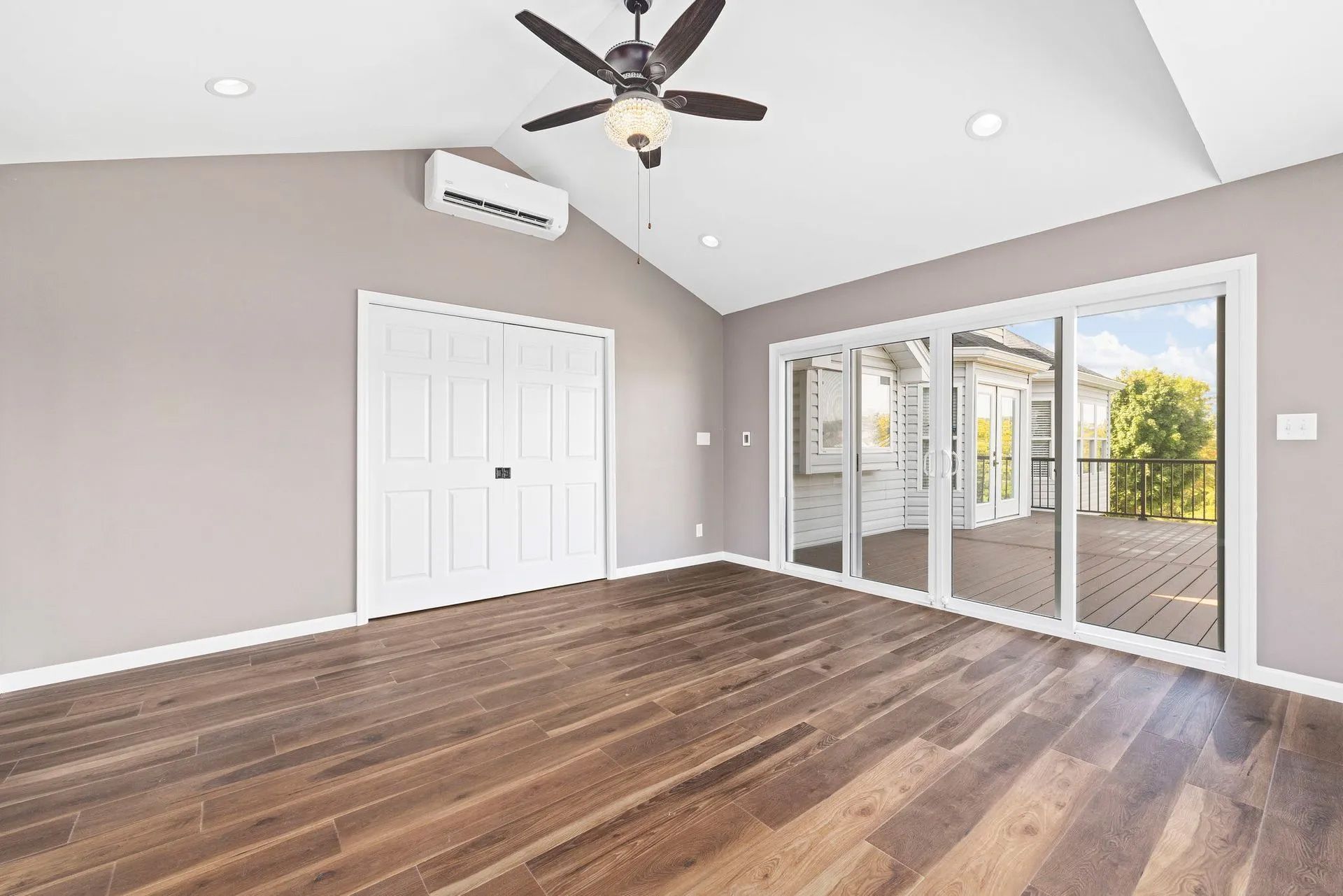 An empty room with hardwood floors and a ceiling fan