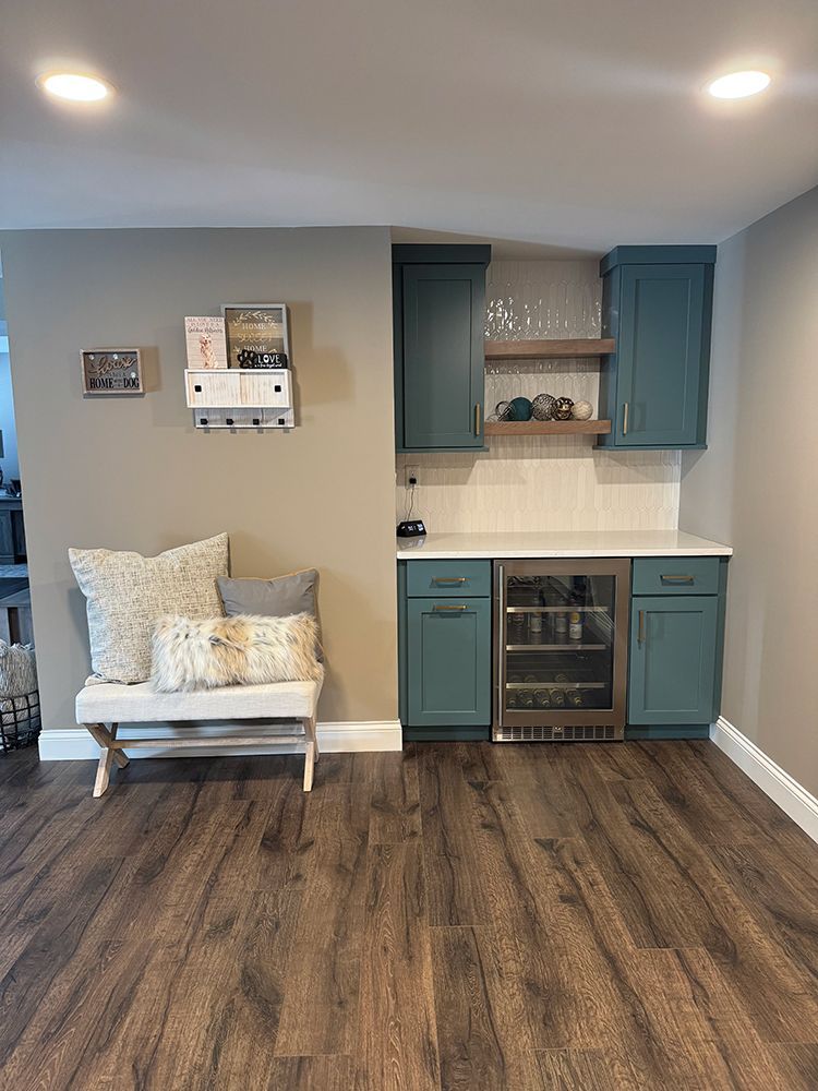 There is a bench in the middle of the room with a refrigerator.