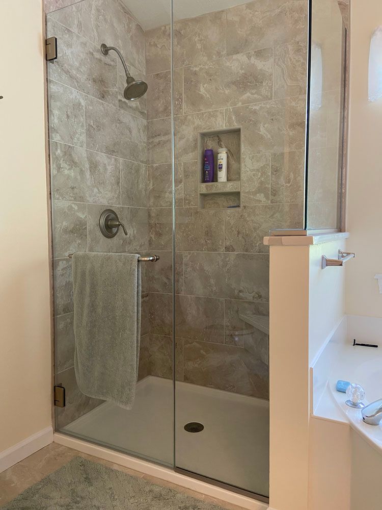A bathroom with a walk in shower with a glass door.