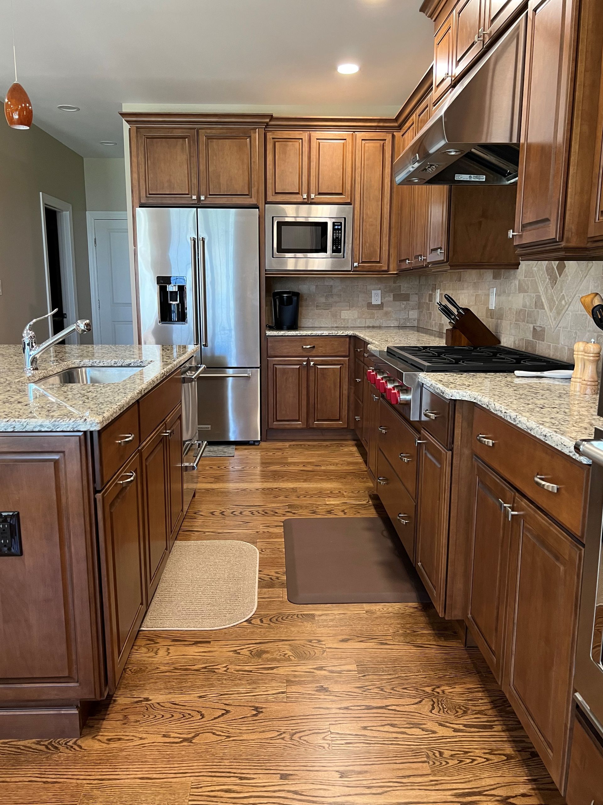 A kitchen with wooden cabinets, granite counter tops and stainless steel appliances.