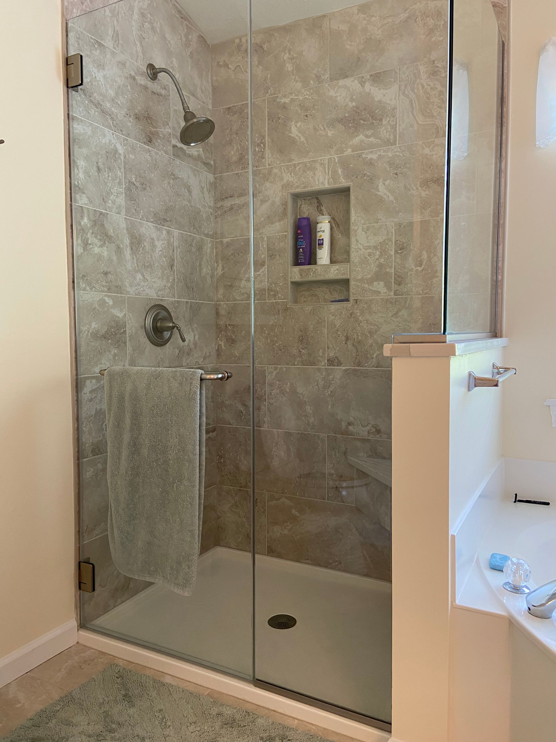 A bathroom with a walk in shower with a glass door.