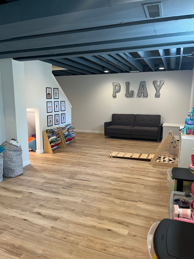 There is a couch in the middle of the room with the word play on the wall