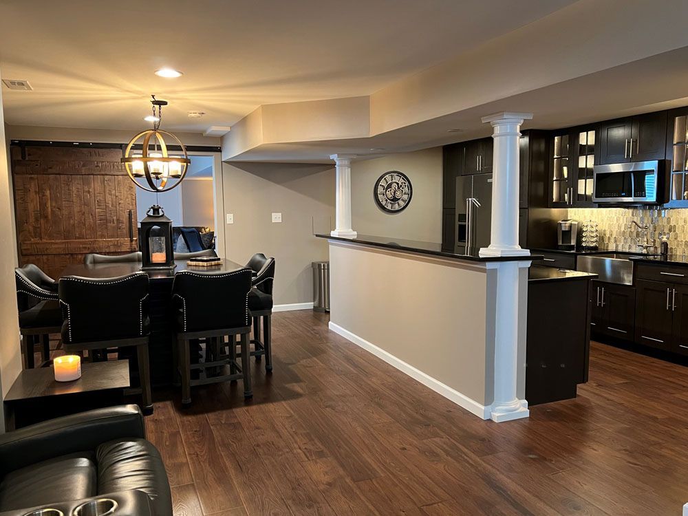 A living room with hardwood floors and a kitchen in the background