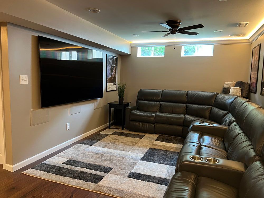 A living room with a couch, television, and ceiling fan