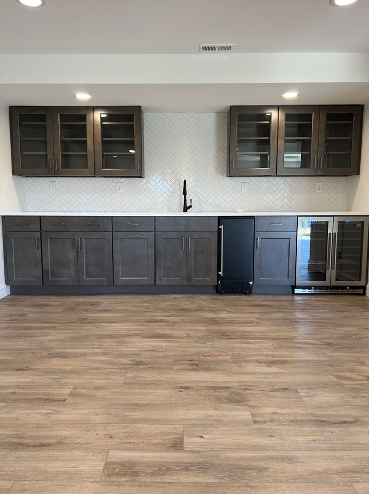 A kitchen with a sink, cabinets, and a refrigerator