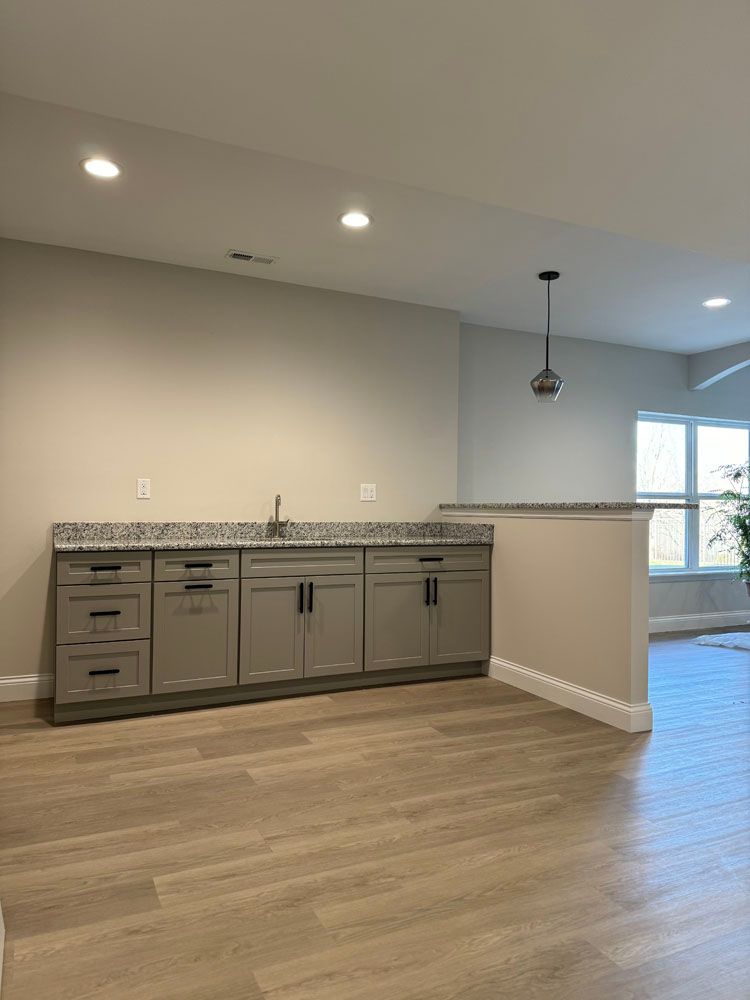 A kitchen with a sink, cabinets, and hardwood floors