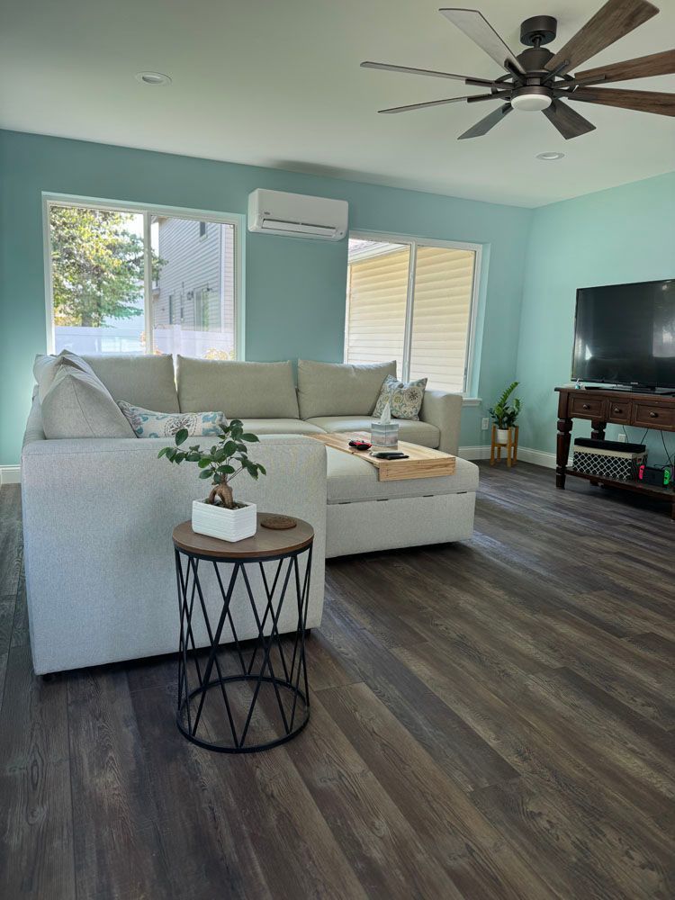 A living room with a couch, table, television, and ceiling fan
