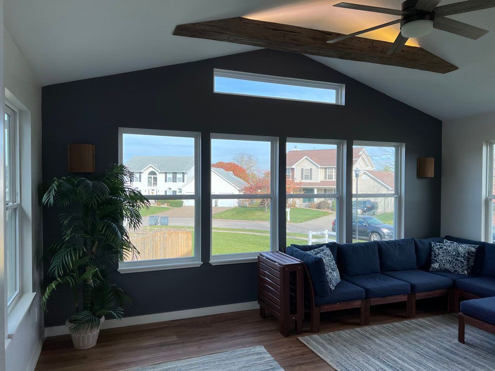 A living room with a lot of windows and a ceiling fan
