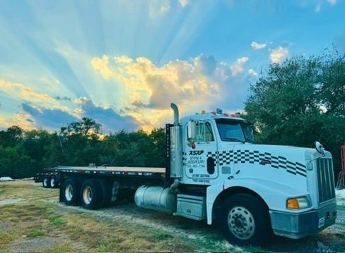 White semi truck parked by a road under a colorful sunset sky