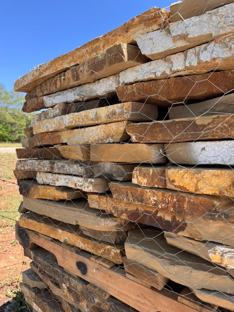 Stacked rough-cut stone slabs outdoors, with a net draped over the pile.