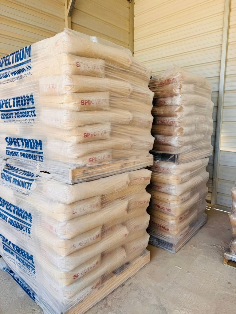 Stacks of bagged goods in a warehouse, with clear and brown wrapped pallets along a wall.