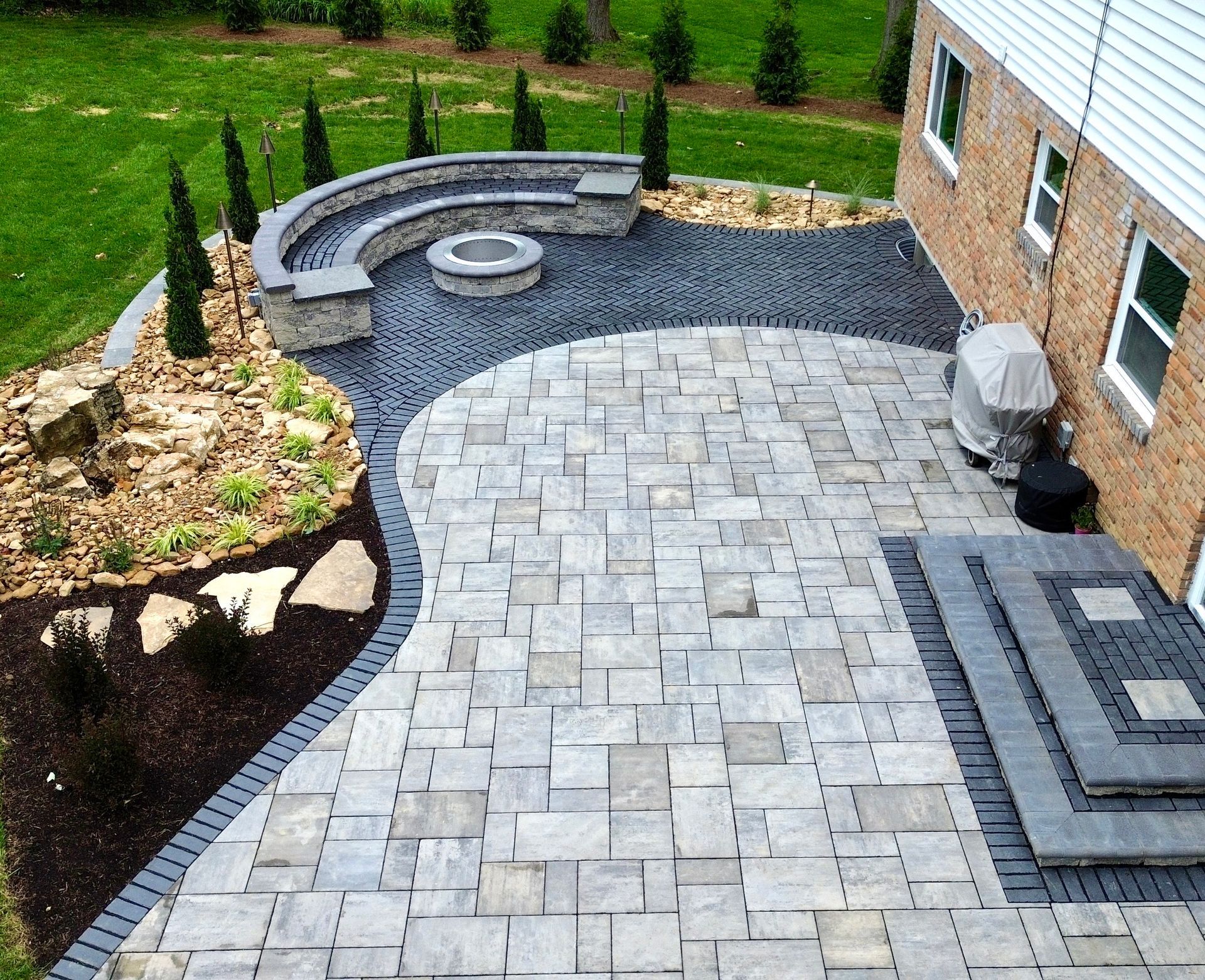 An aerial view of a patio with a fire pit and a bench.