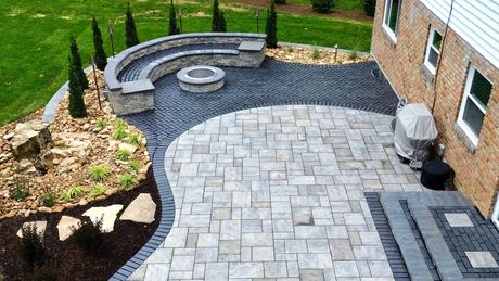 An aerial view of a patio with a fire pit and a bench.