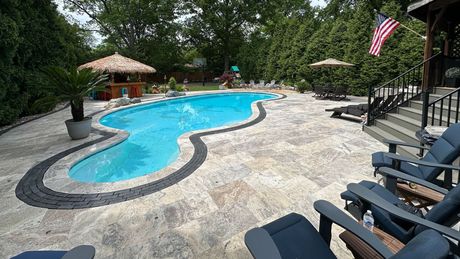 A large swimming pool surrounded by chairs and umbrellas in a backyard.