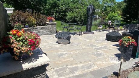 A patio with flowers and a statue in the background