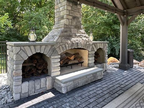 A large stone fireplace is under a wooden gazebo.