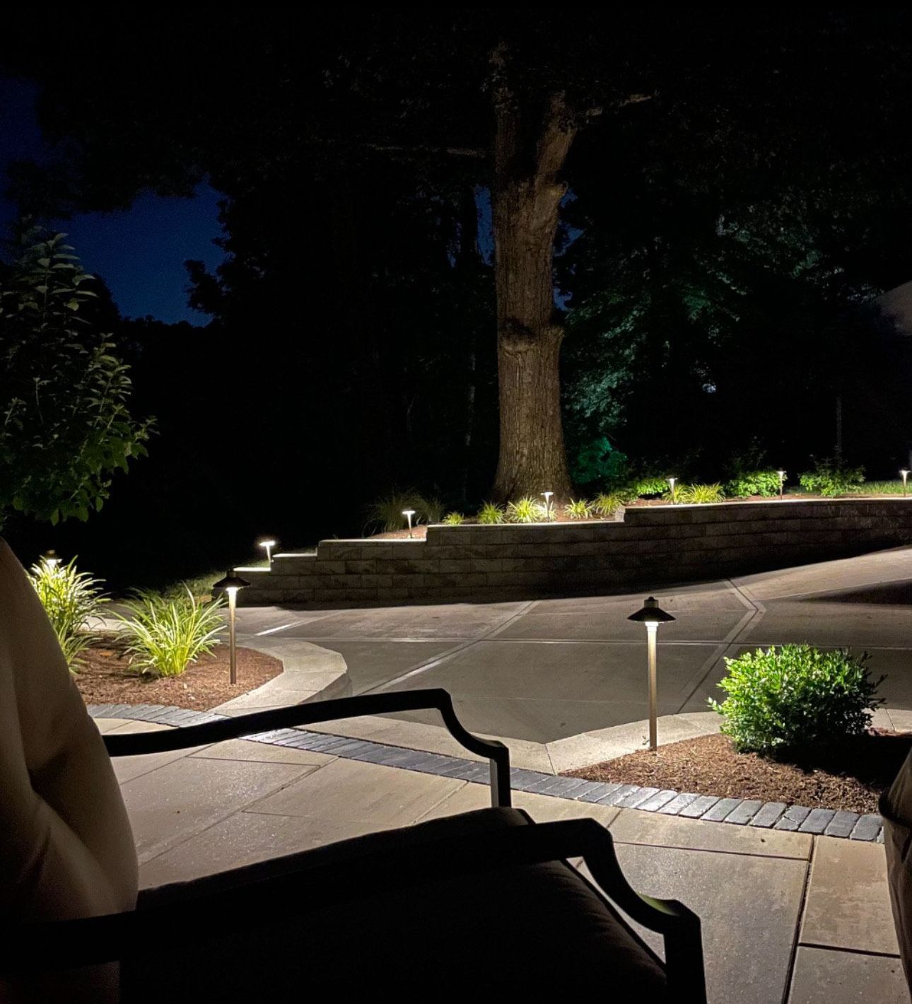 A person is sitting in a chair on a patio at night.