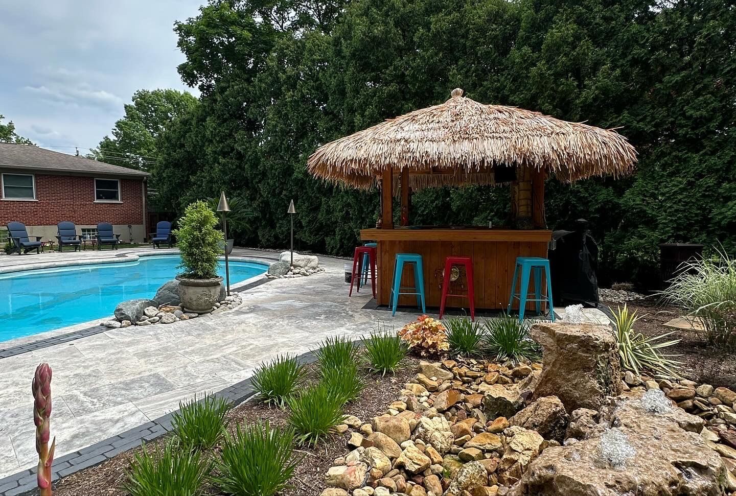 A thatched tiki bar is sitting next to a swimming pool.