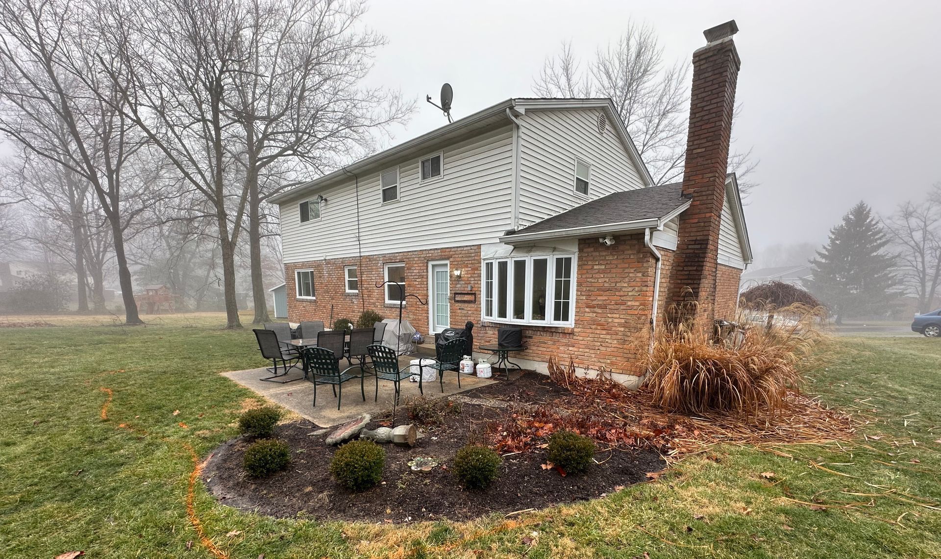 A house with a patio and chairs in front of it on a foggy day.