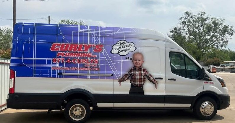 A white van with a picture of a baby on the side is parked in a parking lot.