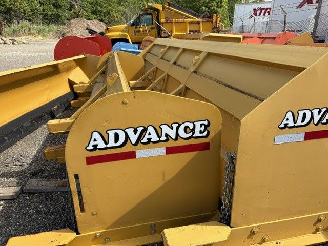 Yellow snowplow, with a truck and other plows in the background.
