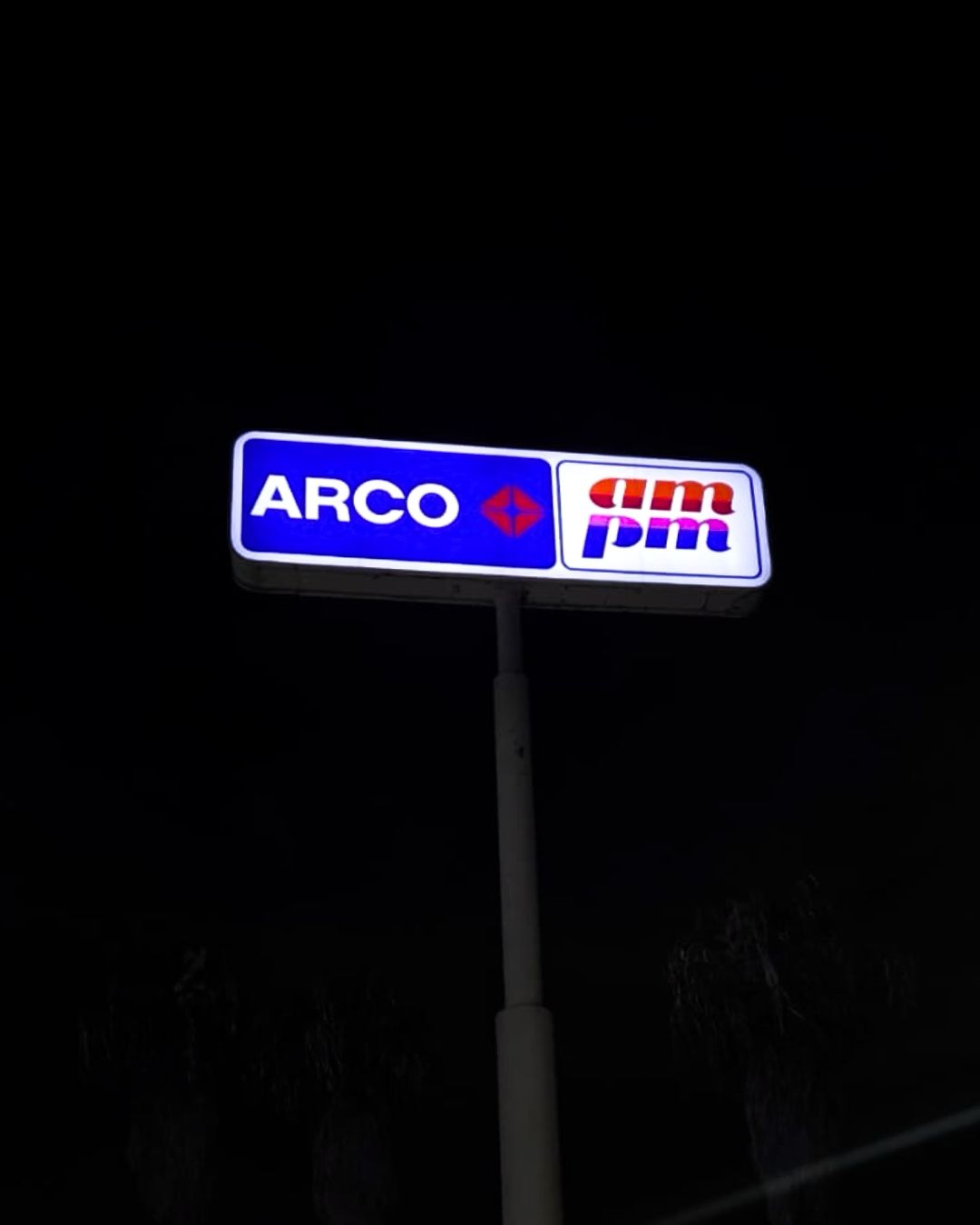 Illuminated ARCO gas station sign on a tall pole at night