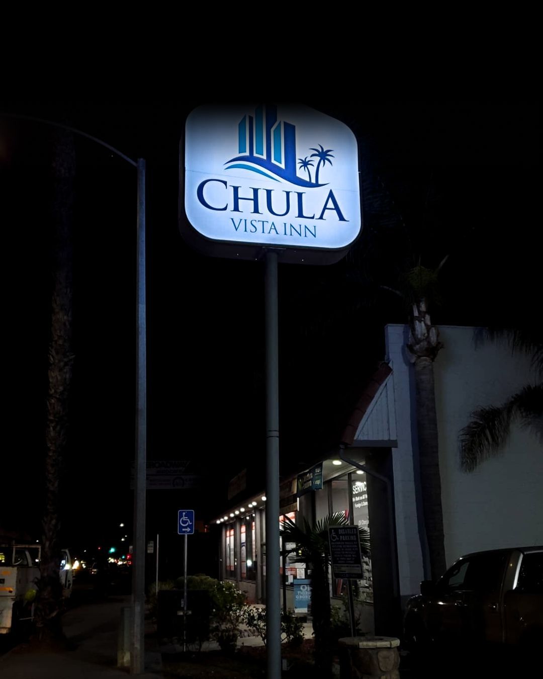 Nighttime exterior of a lit Chula Vista Inn sign beside a building and parked cars