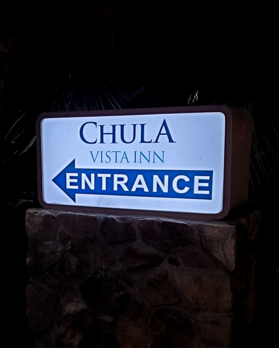 Chula Vista Inn entrance sign on a stone base at night, with blue and white lettering.