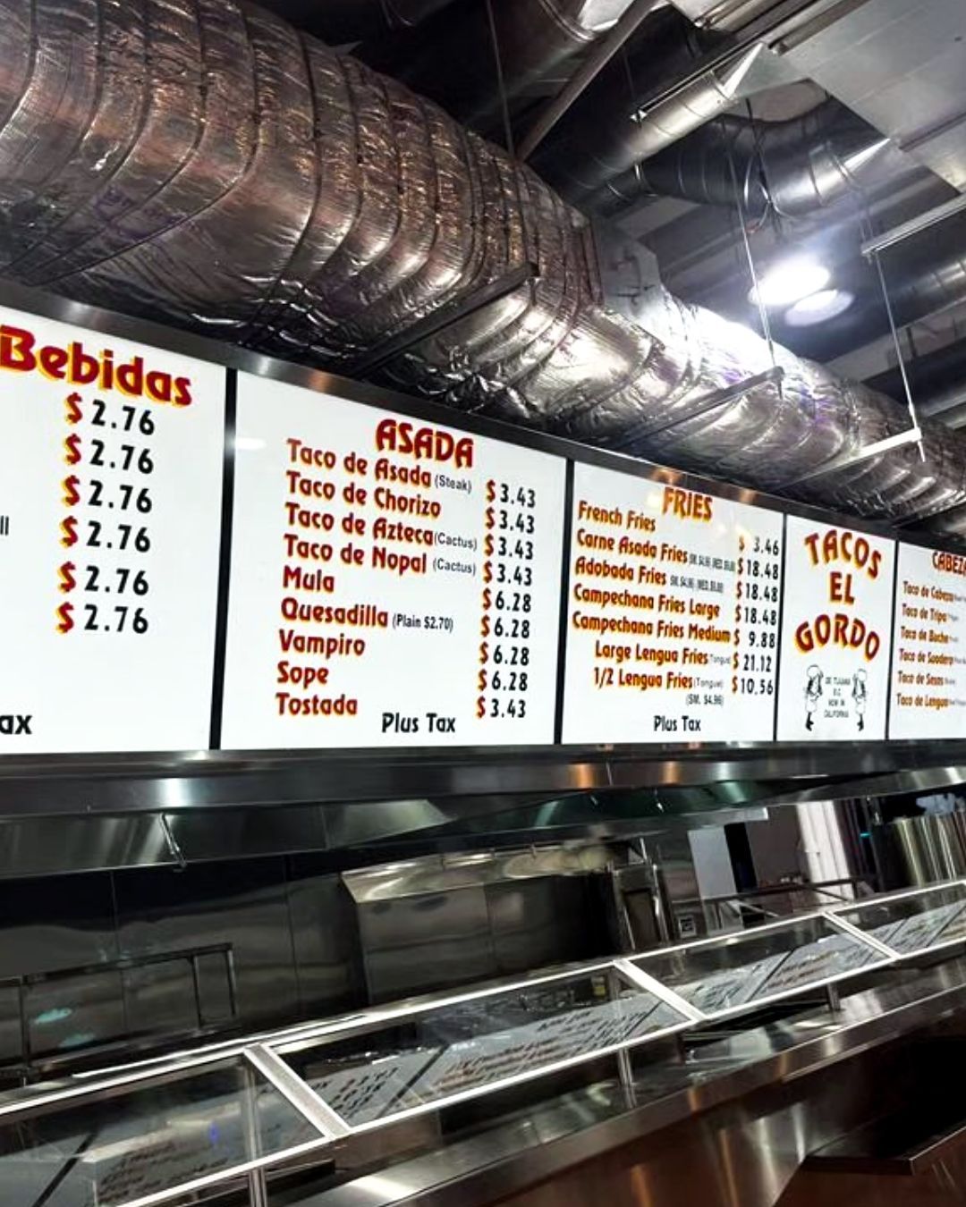 Taquería counter with Spanish menu boards, beverage prices, and silver ductwork overhead