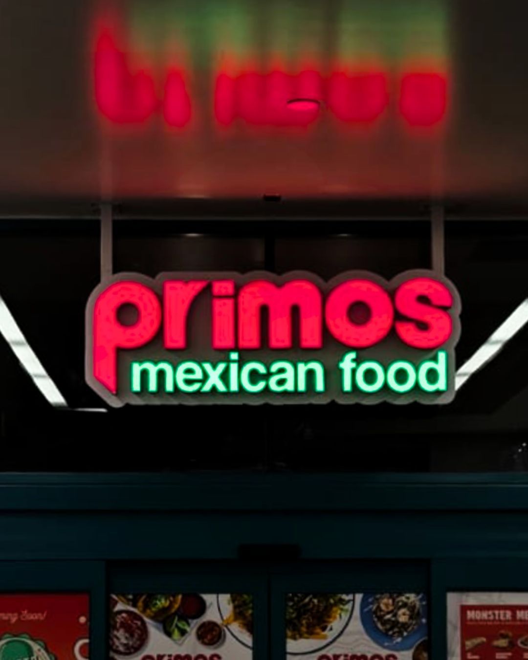 Neon sign for Primos Mexican Food glowing red and green on a storefront at night
