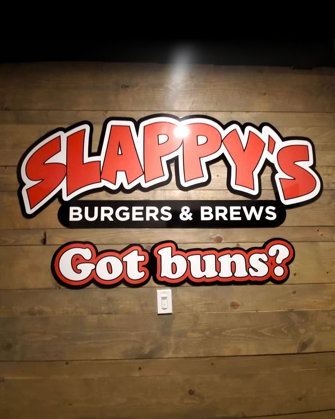 Slappy’s Burgers & Brews sign on a wooden wall with the phrase Got buns?