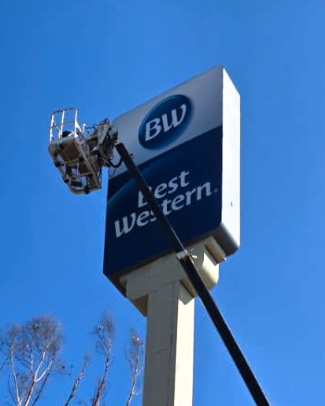 Best Western hotel sign against a blue sky, with a maintenance lift beside it.