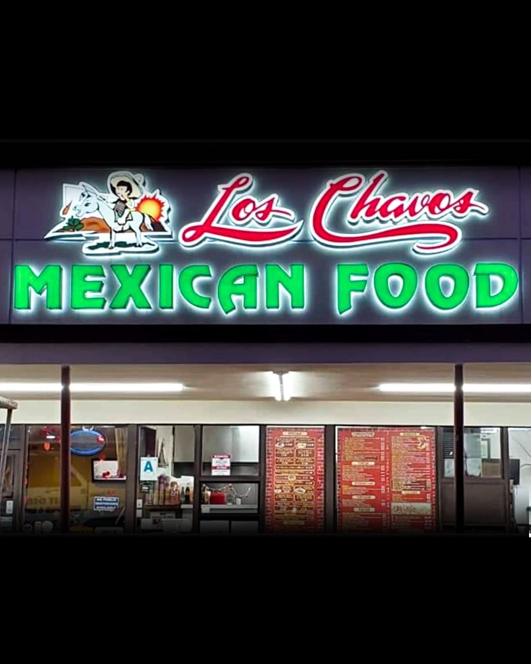 Lit Mexican food storefront sign at night with red and green neon lettering
