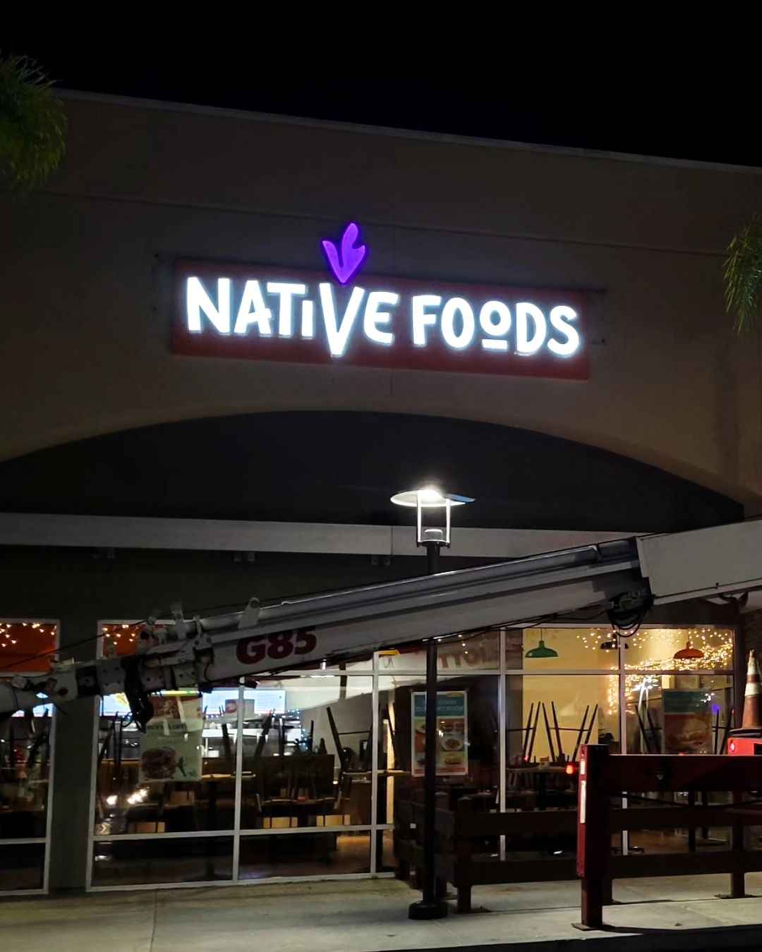 Native Foods restaurant storefront at night with illuminated sign and outdoor seating