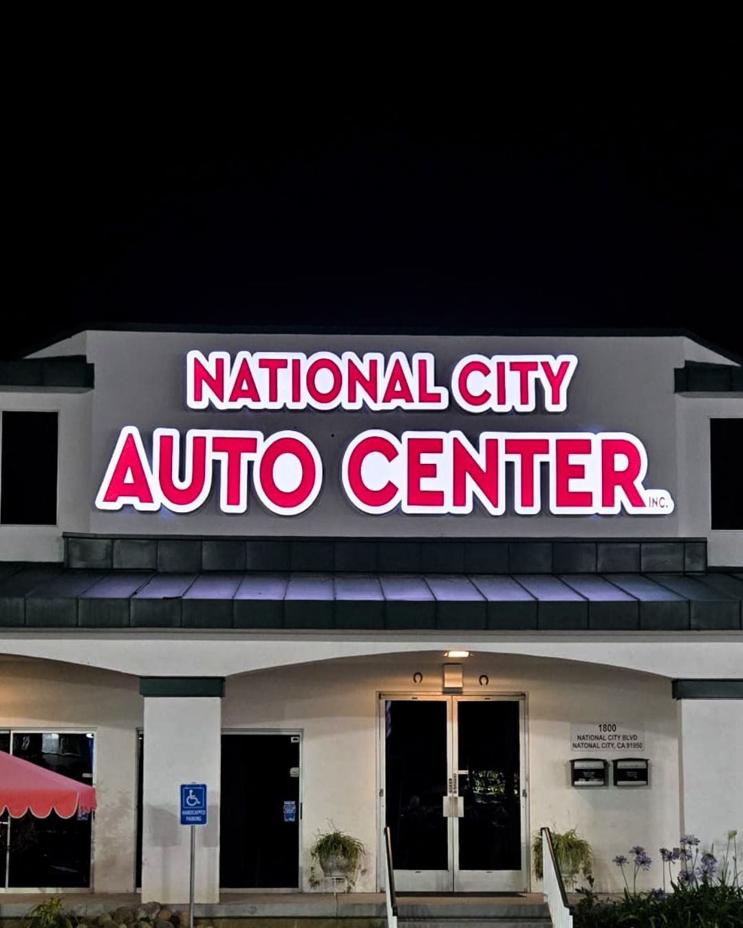 National City Auto Center storefront with bright red and white sign at night