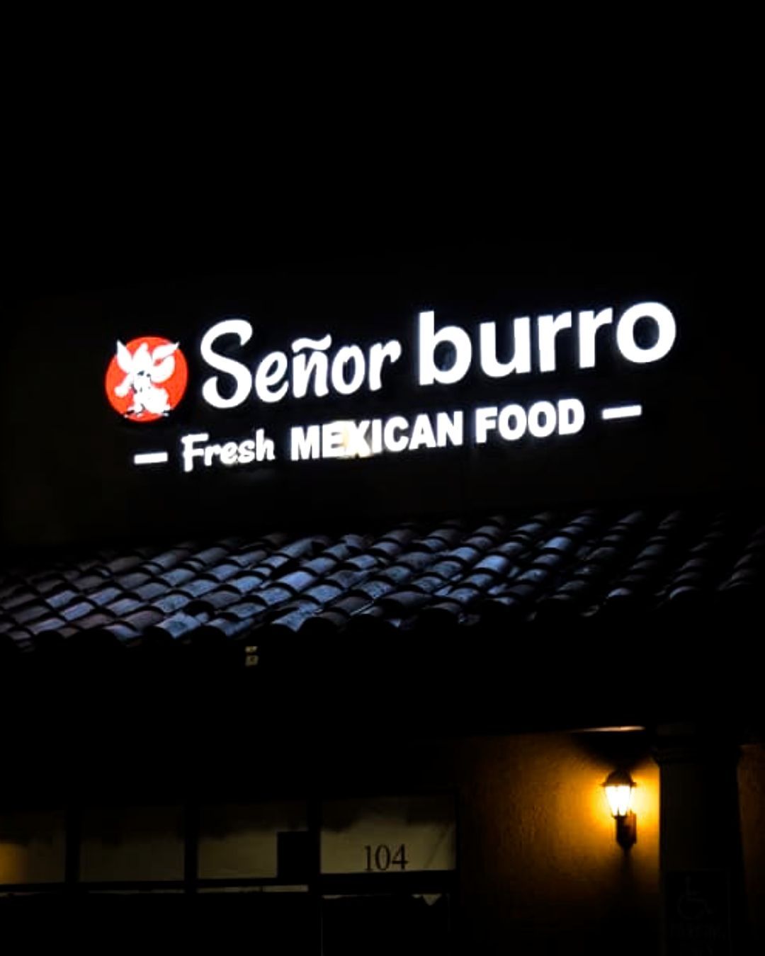 Illuminated Señor Burro Fresh Mexican Food sign above a dark storefront at night